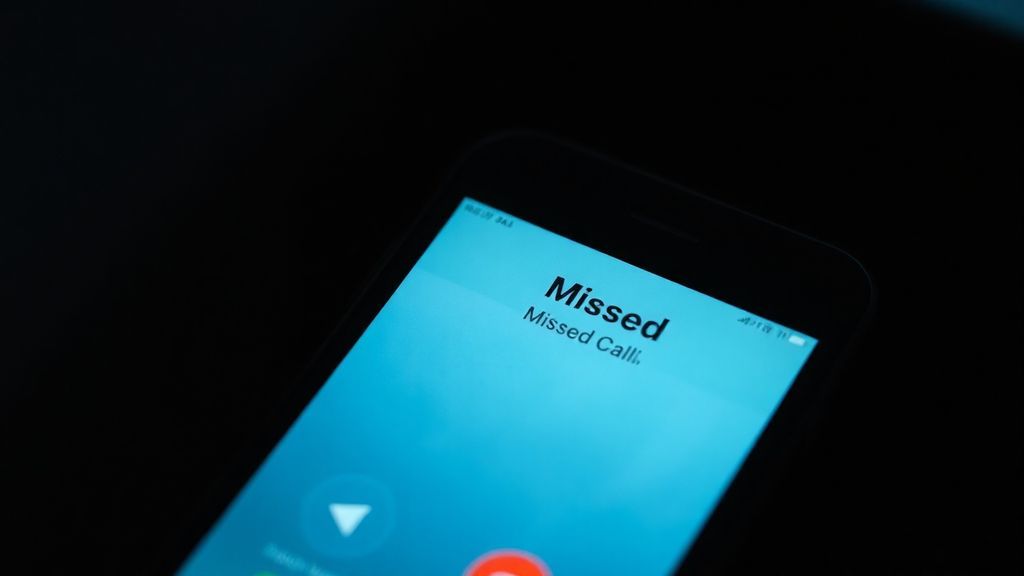 A smartphone showing a single missed call notification on a dimly lit nightstand